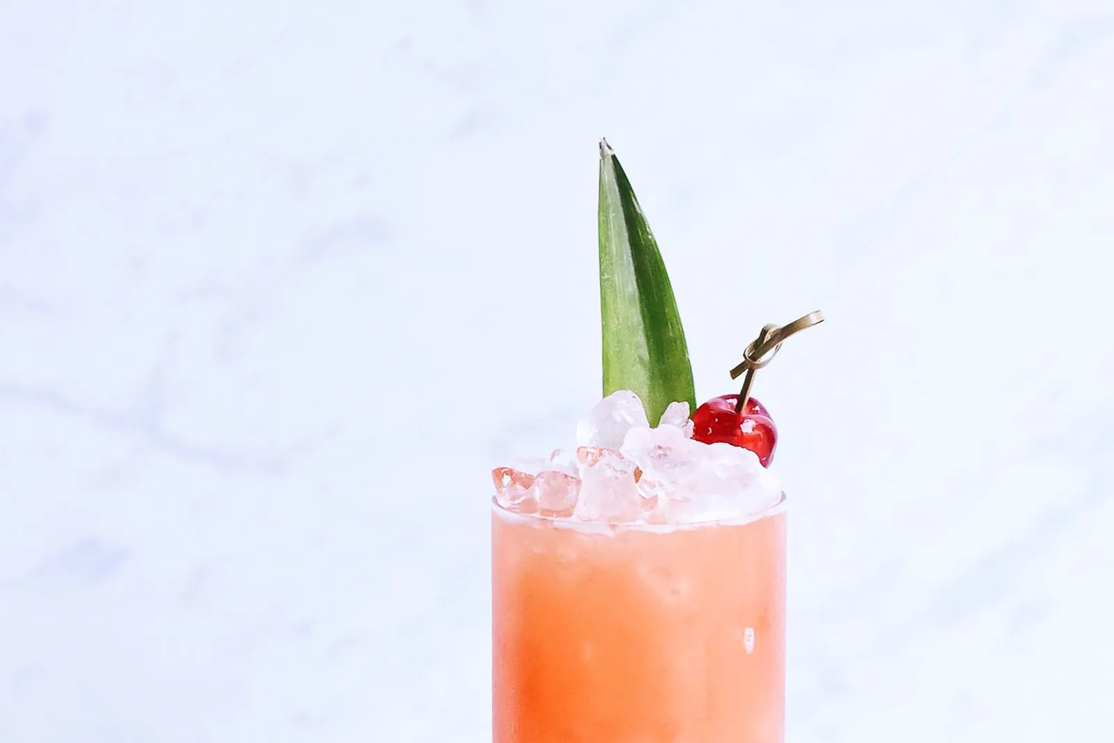 Un cocktail rose avec une feuille d'ananas